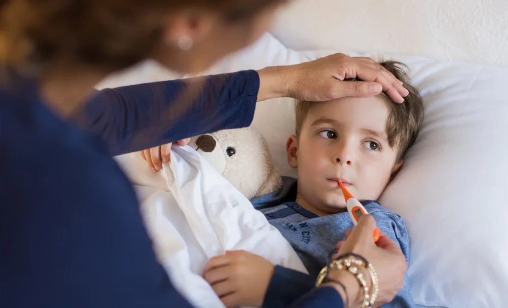 mom taking temperature of sick child in bed with the flu